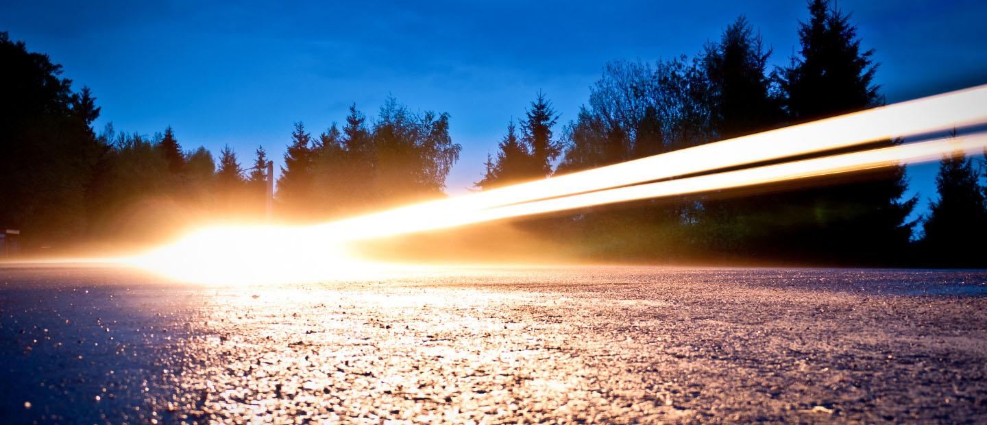 Car headlights beaming over a road at night