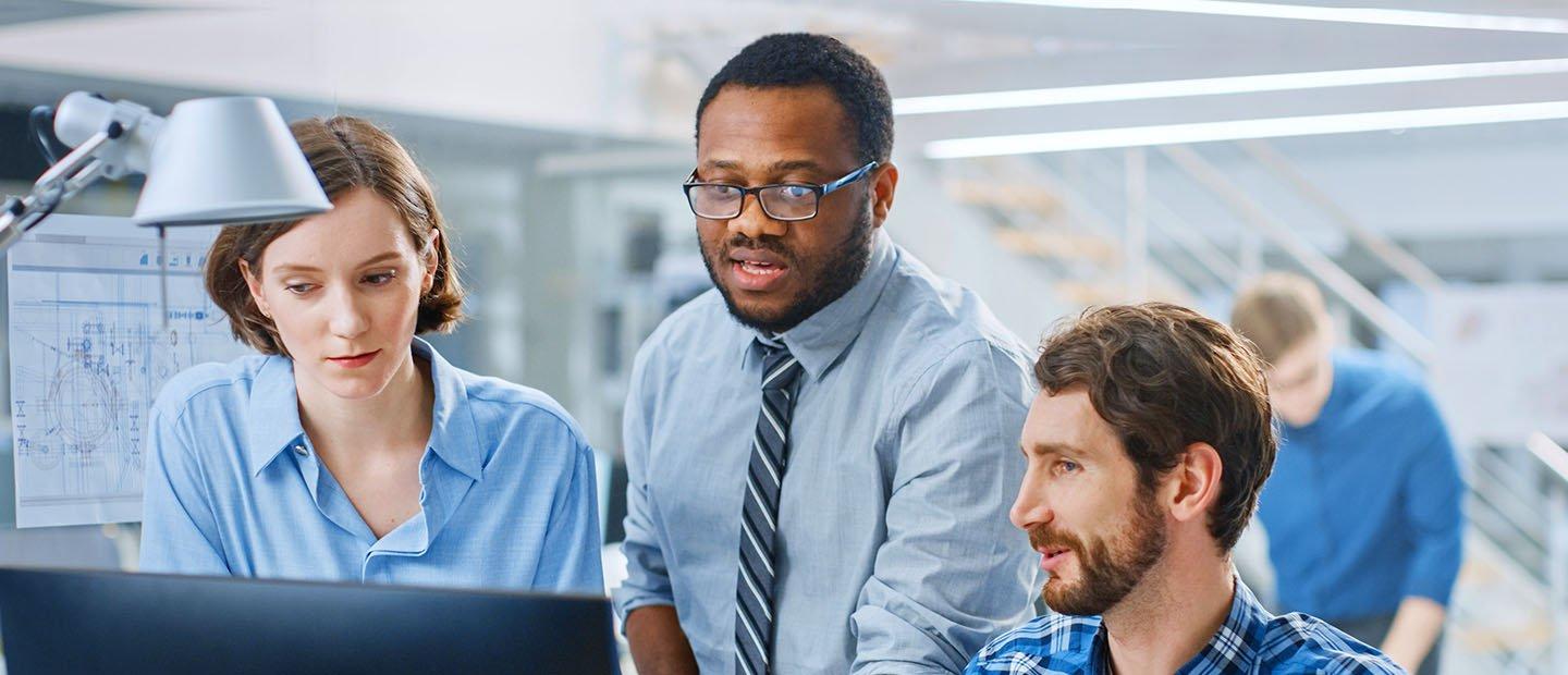 people in blue business attire standing around a computer screen